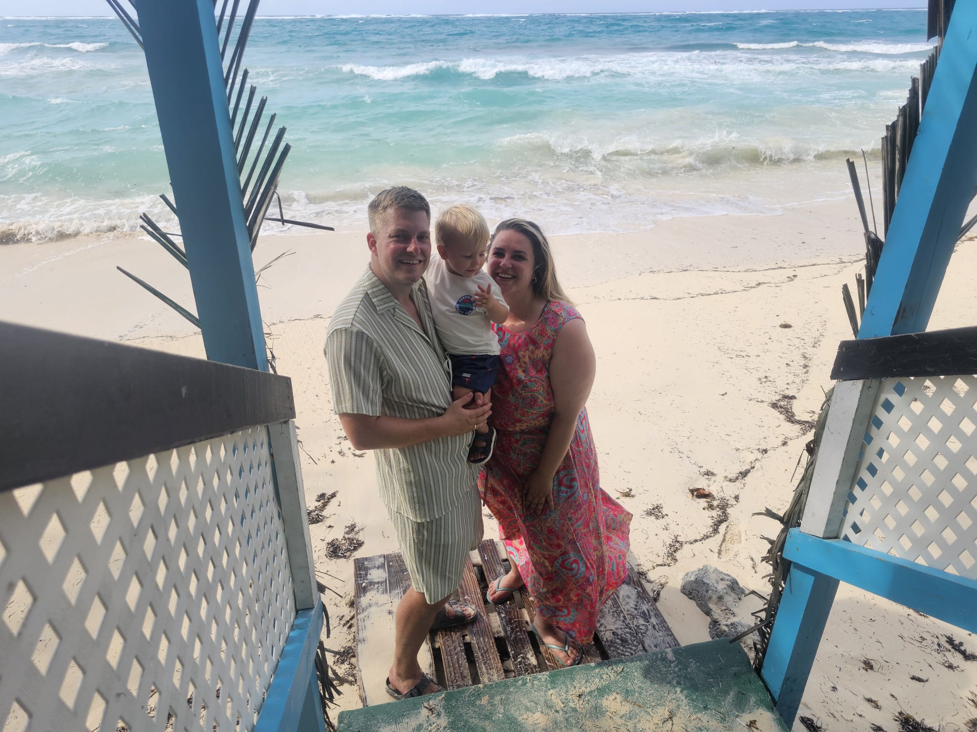 Mitchel, Sissie en Mylo samen op de trap van een kleurrijk strandhuis op de Bahama's